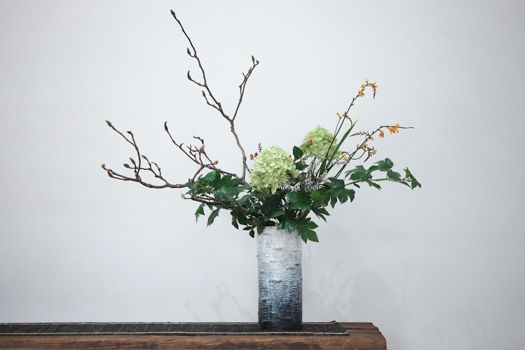 Seizoensboeket met hortensia, groen en takken in hoge vaas