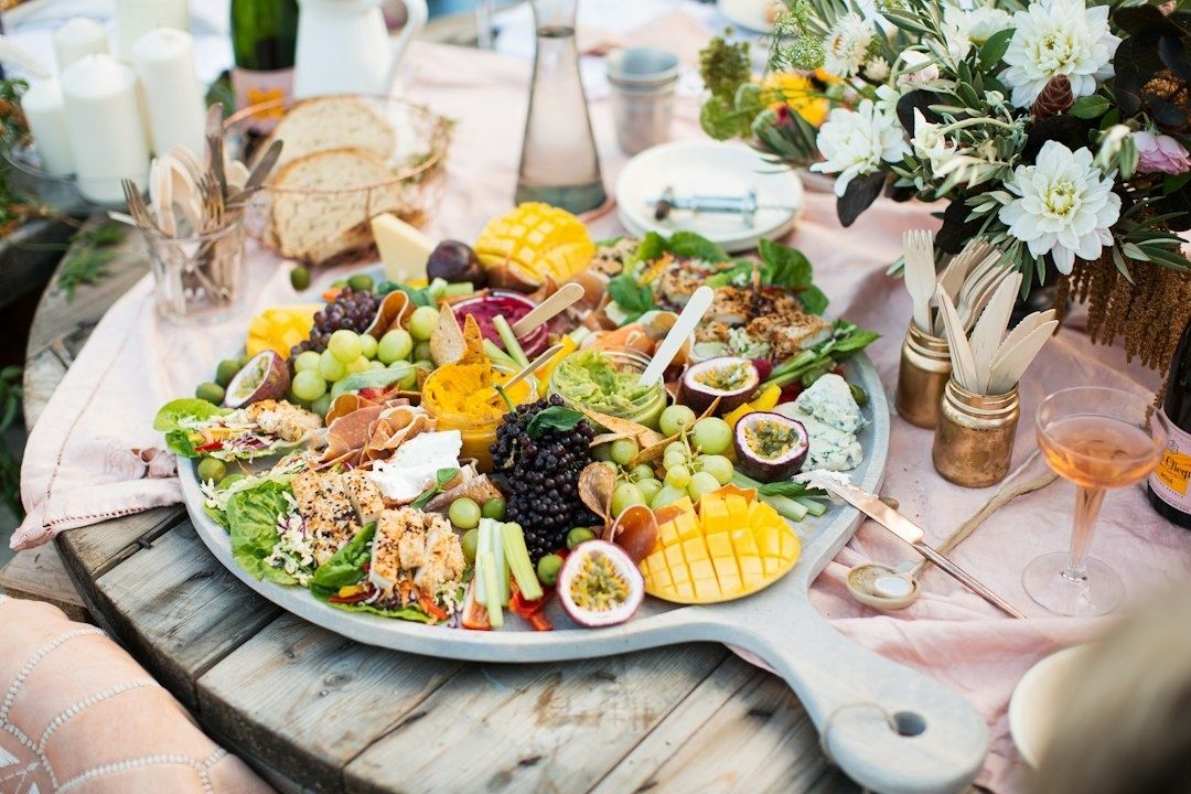 Gedeelde serveerplank met fruit, groenten, dips en brood op een feesttafel